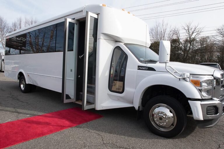 White 24-passenger party bus exterior with red-carpet entry